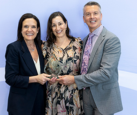 Three people standing together with award