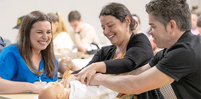 Educator with two people and a baby in a classroom.