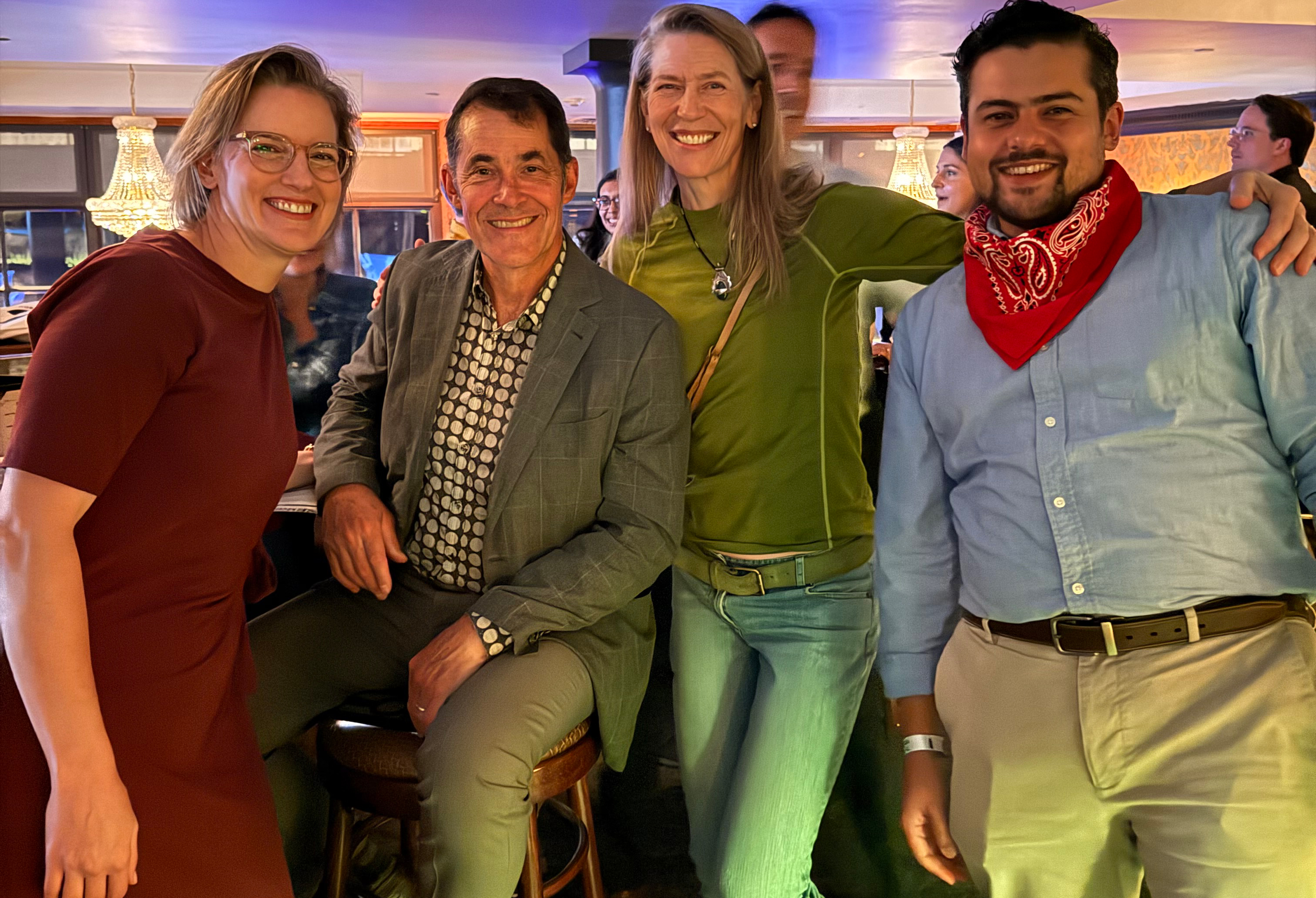 Four people in a casual setting smiling.