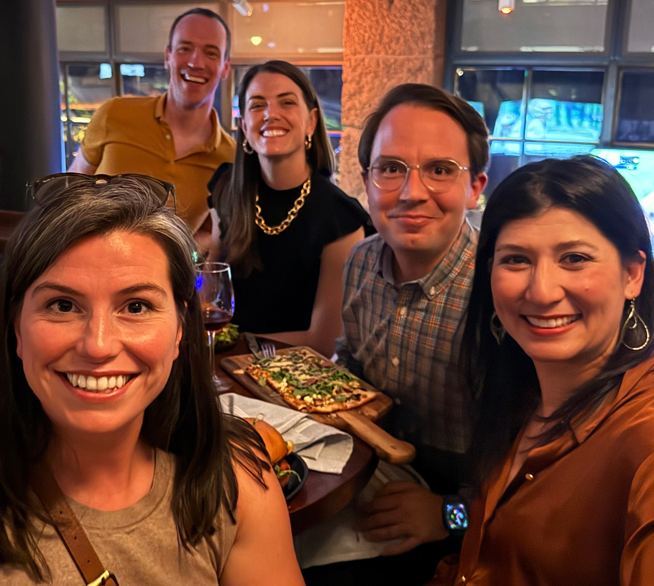 Five people in a casual setting smiling.