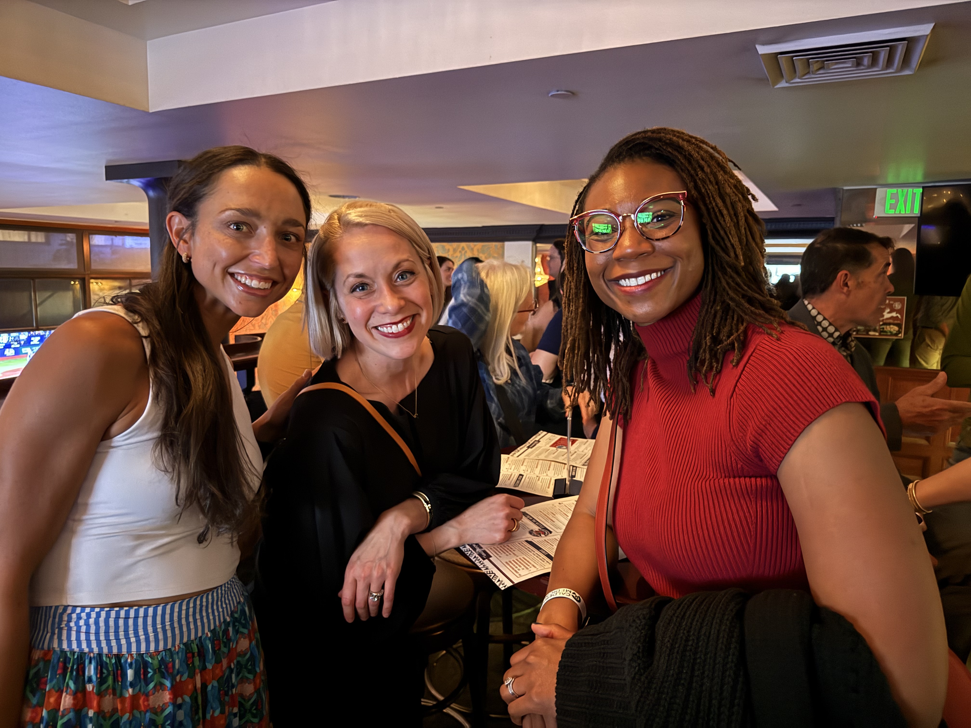 Three people at a conference smiling.