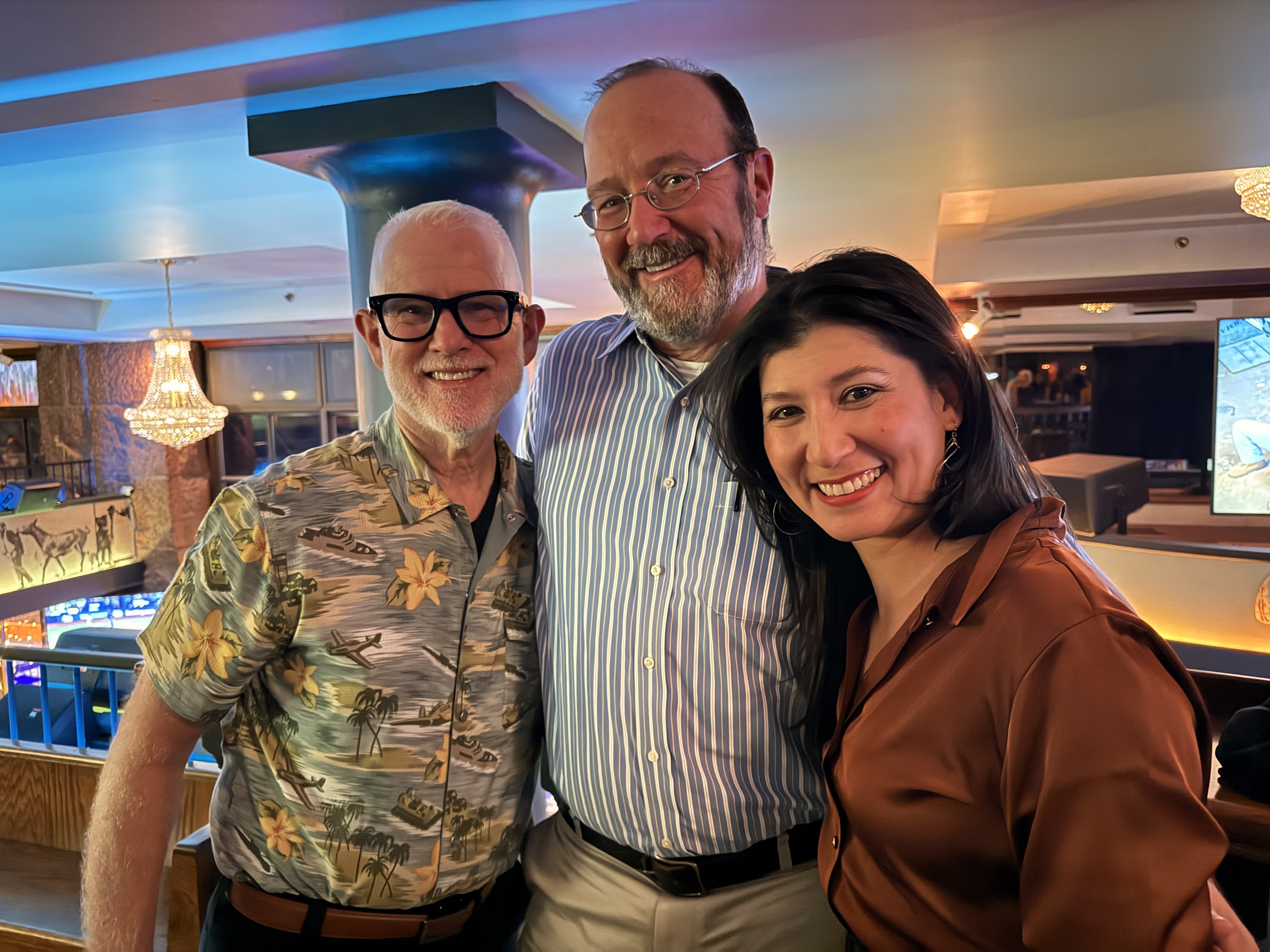 Three people at a conference smiling.