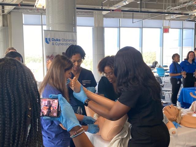 Doctor and students simulating delivering baby with manikin.