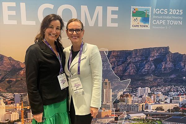 Drs. Angeles Alvarez Secord and Emma Rossi in front of IGCS backdrop.