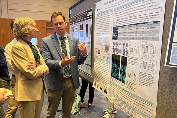 Physician and researcher discussing research poster at symposium.
