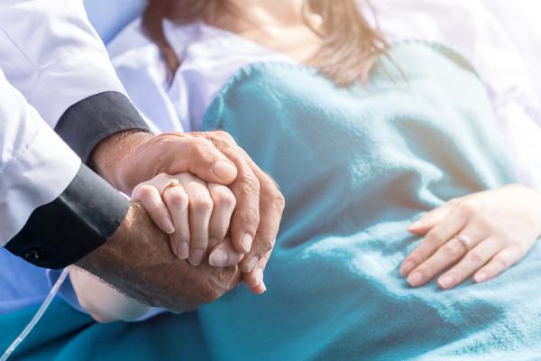 Woman getting cancer treatment holding hands with physician