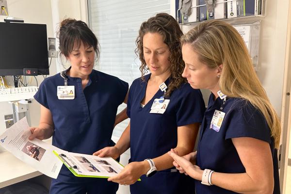 Three therapists in patient room looking at instructions.