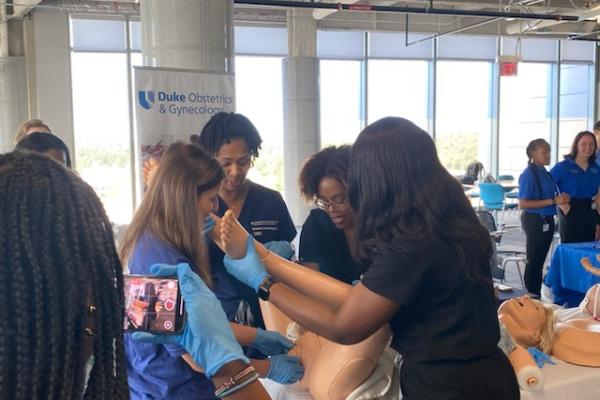 Doctor and students simulating delivering baby with manikin.