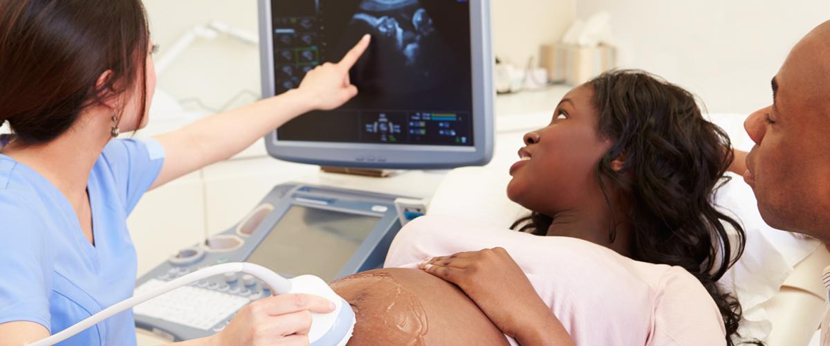 Pregnant patient, sonographer and man looking at ultrasound.
