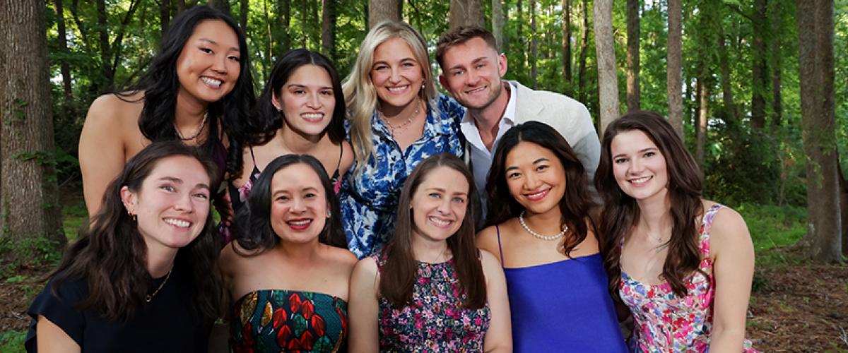 Group of people surrounded by trees smiling.