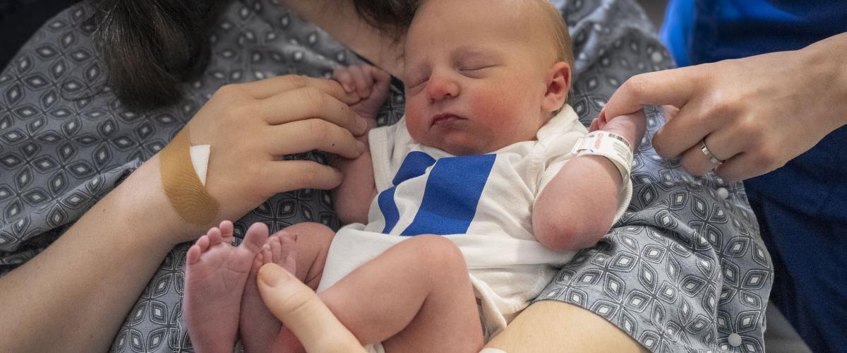 Newborn baby in a Duke onesie with mother