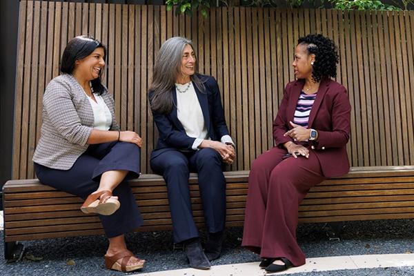Three Duke faculty sitting in courtyard having discussion. 