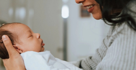 Woman holding infant and smiling.