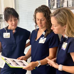 Three therapists in patient room looking at instructions.