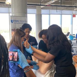 Doctor and students simulating delivering baby with manikin.